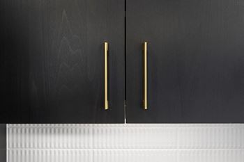 A close up of two black cabinets with brass handles